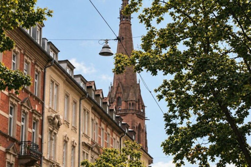 A church steeple, a street lamp, and a tree with green leaves. 3