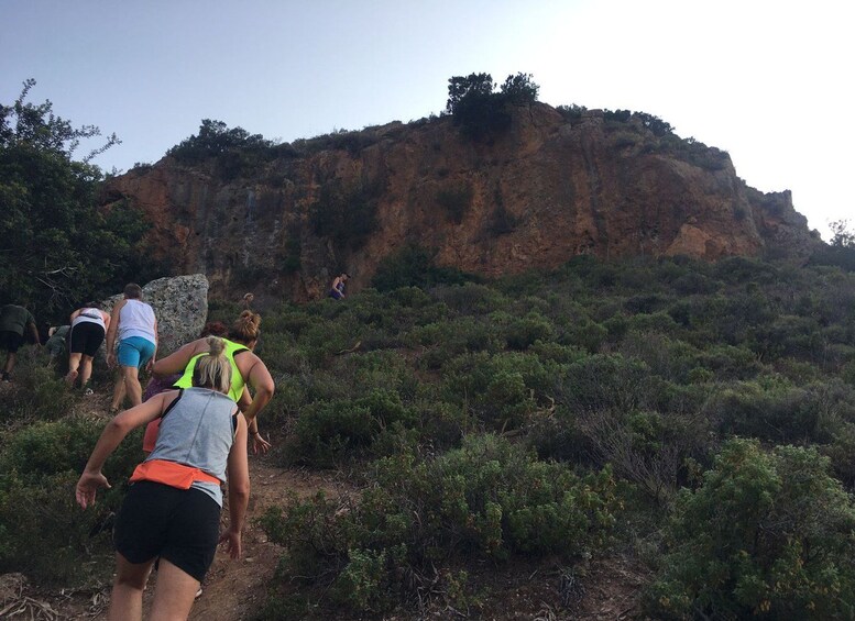 A group of hikers ascending a rocky hillside with sparse vegetation. 1