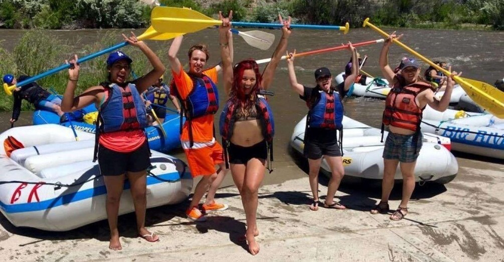People in inflatable rafts on a riverbank, holding paddles. 2
