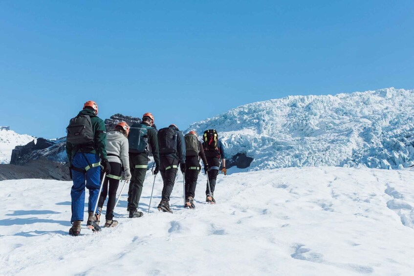 A group of people hiking on a snowy mountain with a clear blue sky. 2