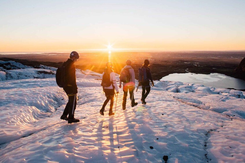 A group of people hiking on a snow-covered mountain at sunset. 1