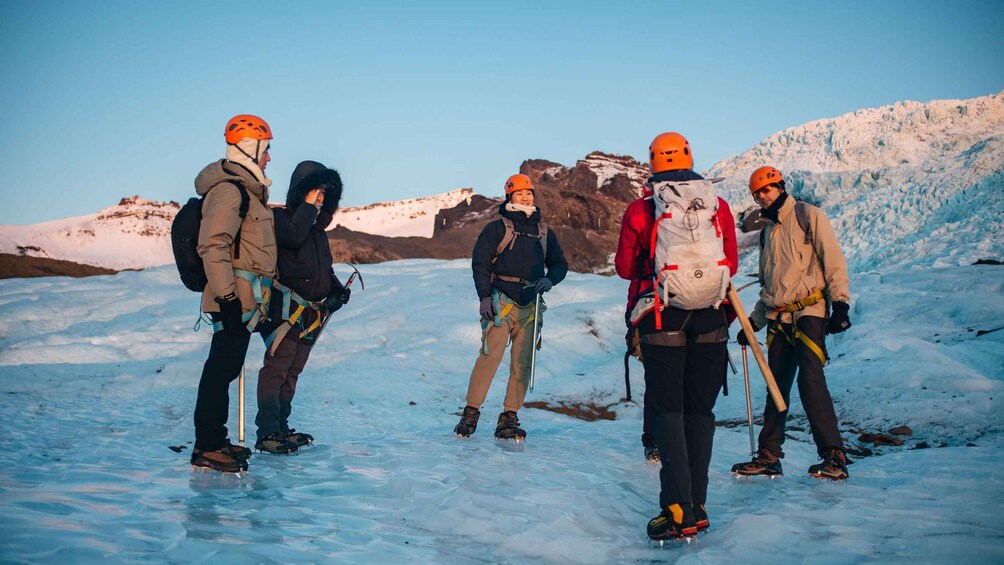 A group of people on a glacier with ice tools, wearing helmets and backpacks. 5