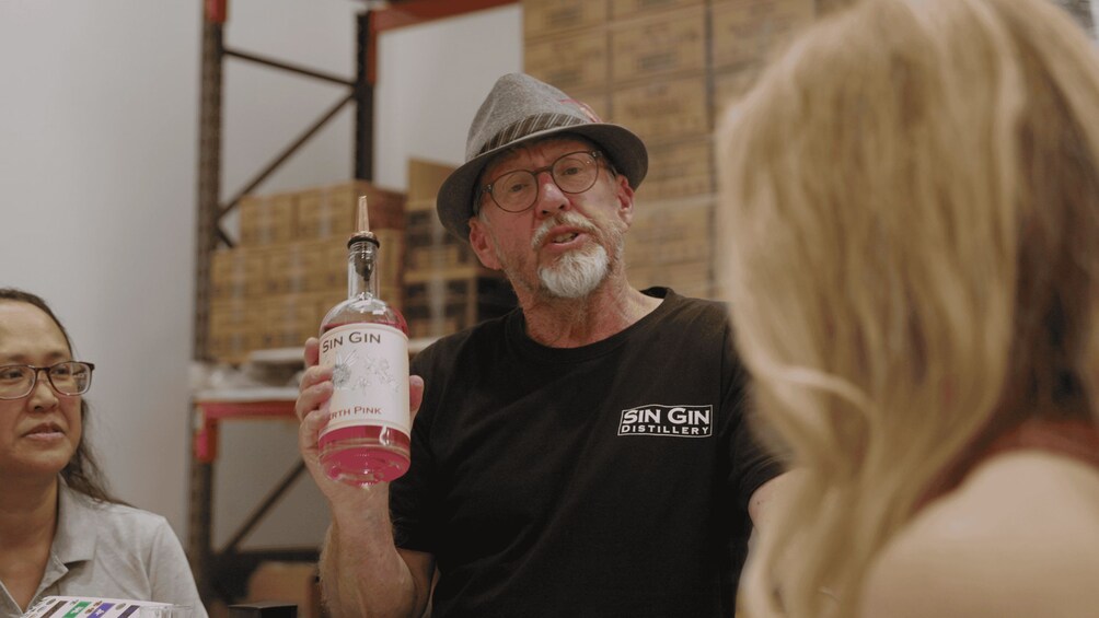 A person holding a bottle of gin in a warehouse setting. 4