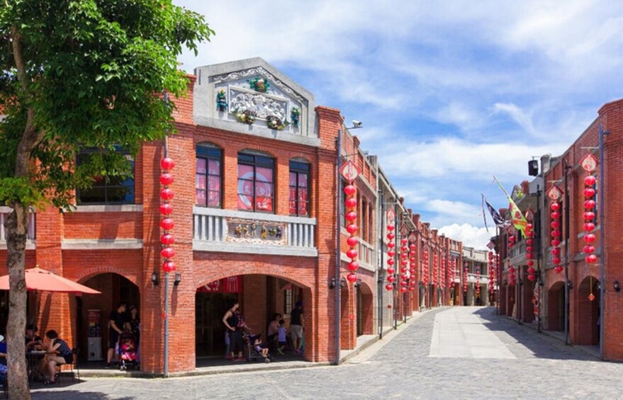 A brick building with red lanterns, a balcony, and a cobblestone street. 4