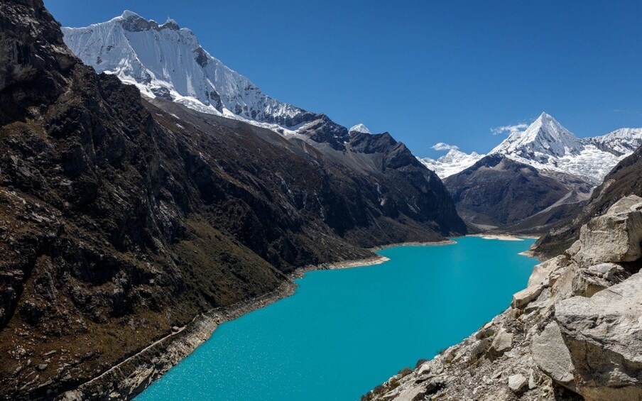 A turquoise lake surrounded by rugged mountains with snow-capped peaks. 5