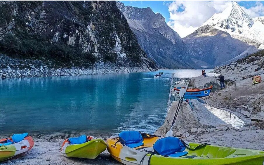 Kayaks on a shore, a boat on the water, and a mountainous landscape. 2