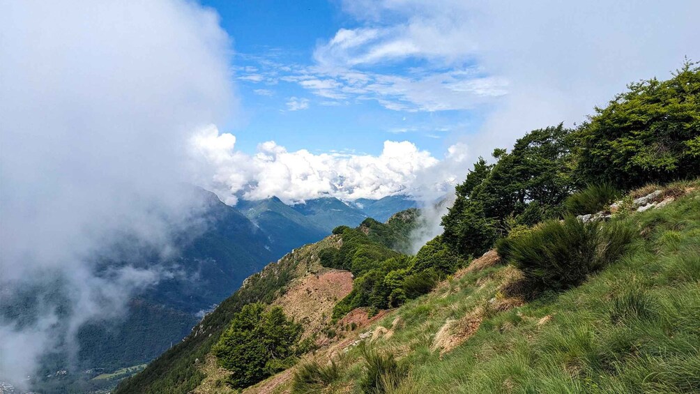 A mountainous landscape with lush greenery, a clear sky, and clouds partially covering the peaks. 5