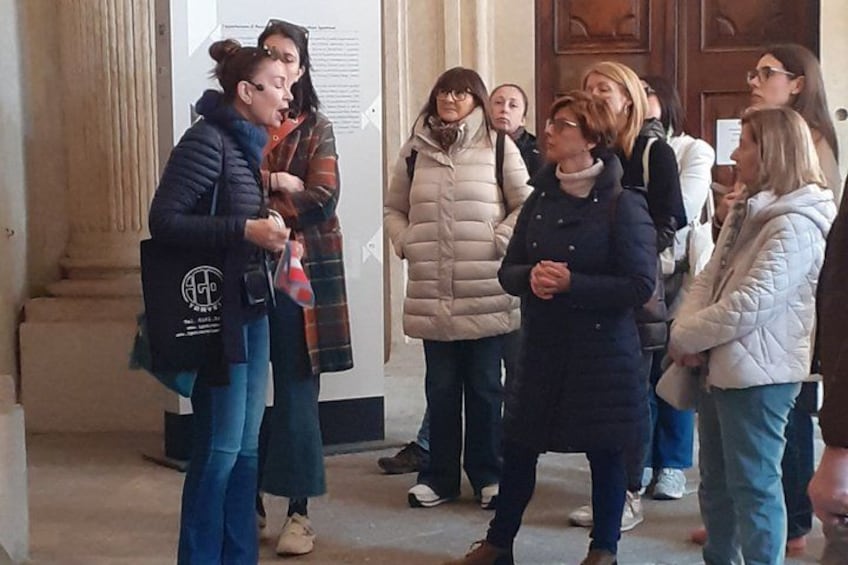 A group of people standing in a hallway with columns and a wooden door. 4