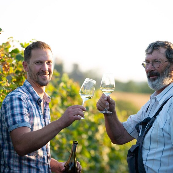 Two people toasting with wine glasses in a vineyard. 3