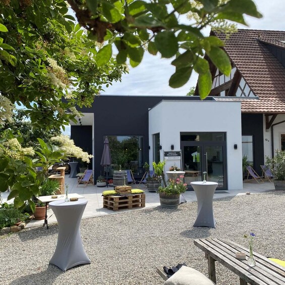 An outdoor seating area with tables and chairs, surrounded by potted plants and a building with a modern design. 2