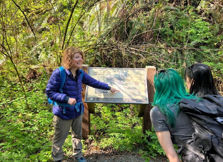 A person pointing at a sign in a forested area. 2