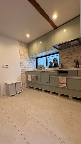 Una cocina moderna con gabinetes verdes, una pared de acento de ladrillo y una ventana sobre el lavabo. 3