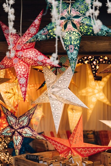 A collection of decorative paper stars with intricate patterns and LED lights, displayed in a wooden crate. 2