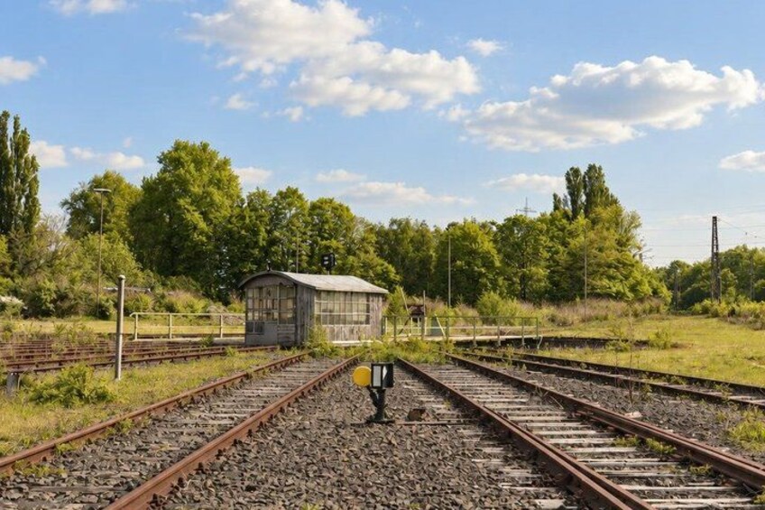 Railway tracks, a small wooden structure, and trees in a rural setting. 2