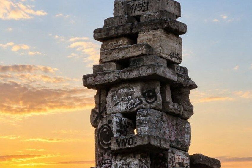 A stone structure with graffiti, set against a sunset sky. 5