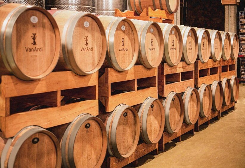 Wooden wine barrels stacked in rows, each with a label. 3