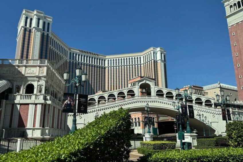The Venetian Hotel with a distinctive arched bridge and a tall building in the background. 2