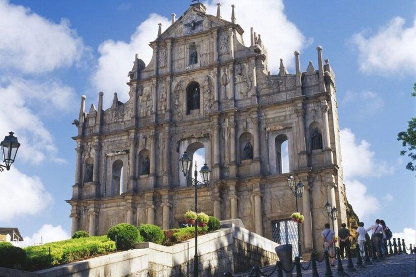 A historic cathedral with intricate architecture, a staircase leading up to it, and a clear blue sky. 3