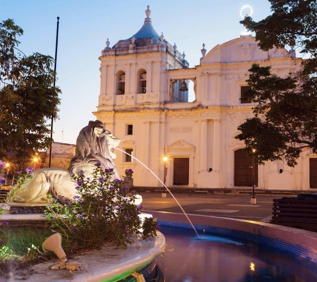 A historic building with a bell tower and a fountain with a statue. 2
