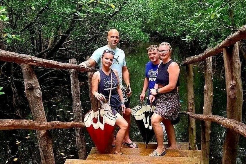 A group of people on a wooden bridge in a forested area. 2