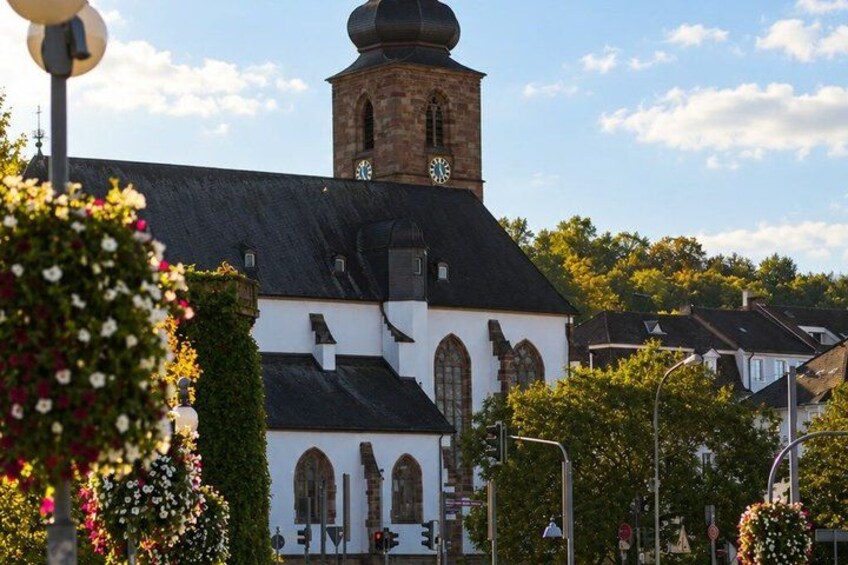 A church with a clock tower, surrounded by trees and flowers. 4