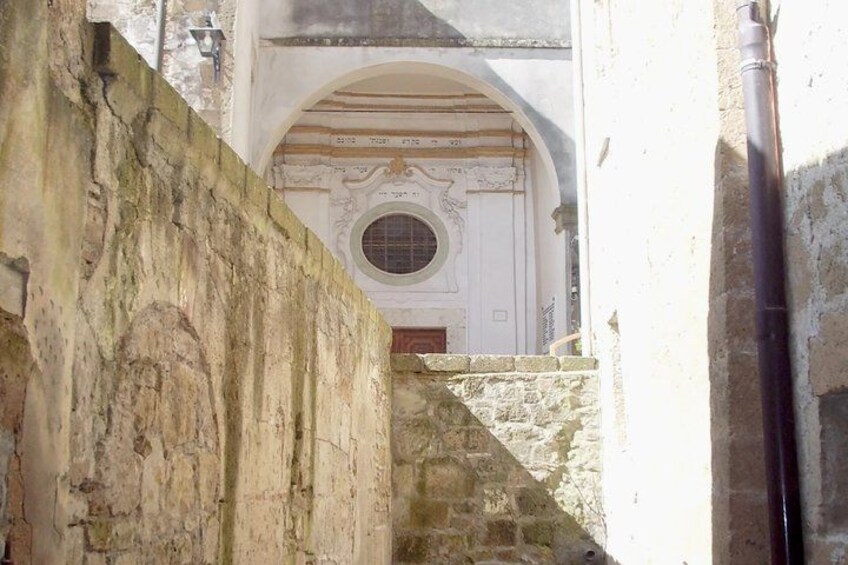 A stone wall, a doorway with a circular window, and a building facade with decorative elements. 5