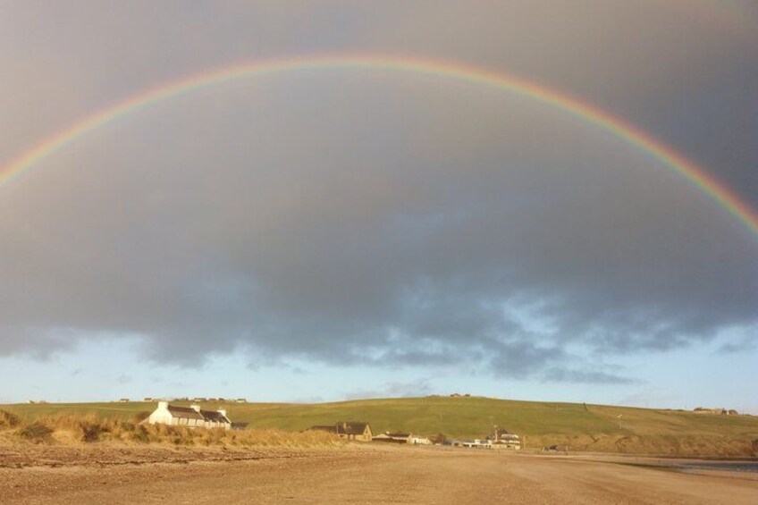 A rural landscape with a rainbow, a dirt road, and a white house. 4