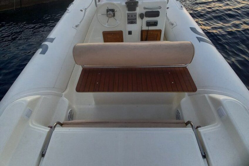 A boat's interior with a cushioned seat, control panel, and storage compartments. 4