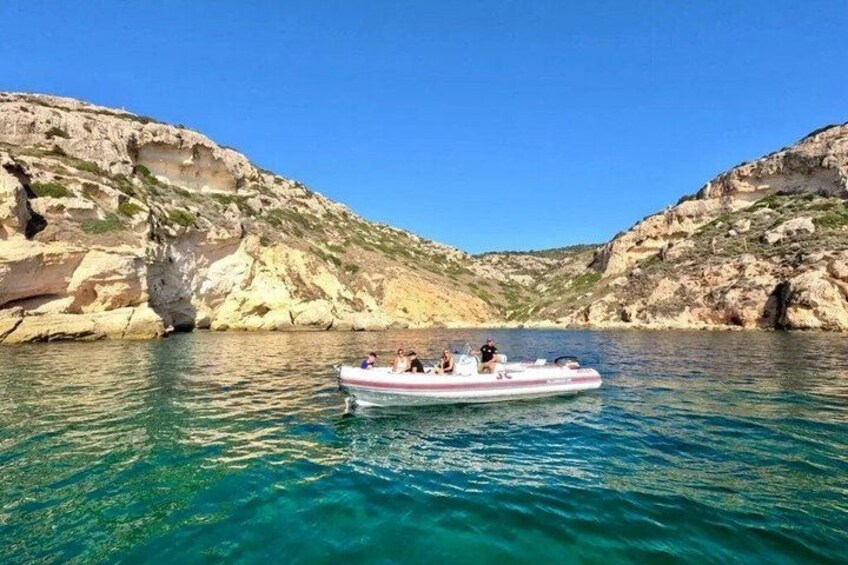 A boat on clear turquoise water surrounded by rocky cliffs. 5