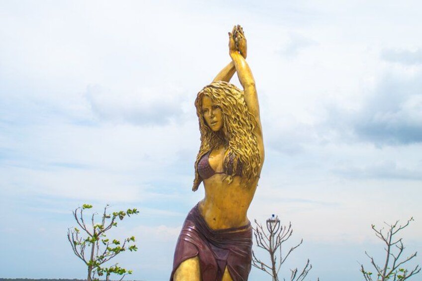 A golden statue of a woman with raised arms, set against a cloudy sky. 2