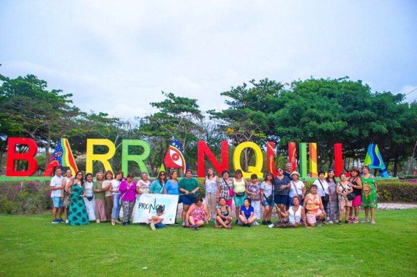 A group of people standing in front of a sign with colorful letters spelling 'BARRANQUILLA'. 5
