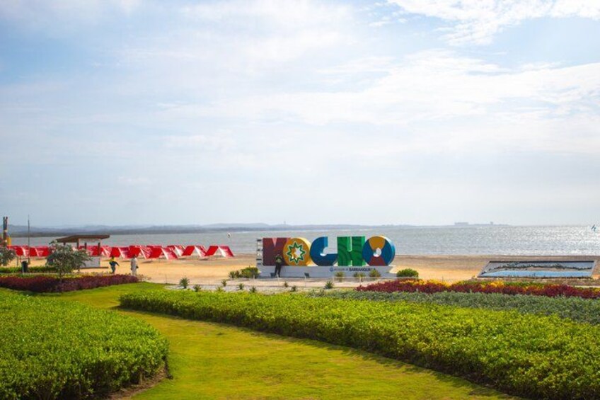 A beach with a colorful sign, a pathway, and a view of the sea. 3