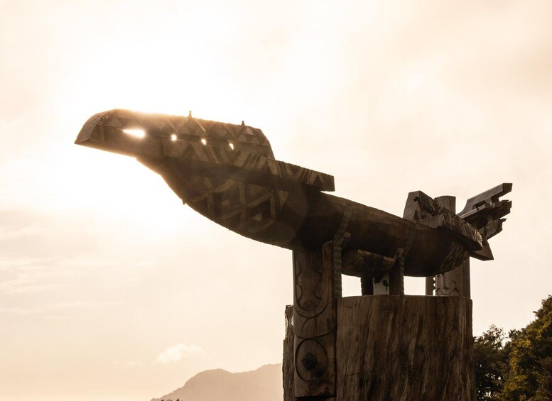 A large wooden sculpture of a bird with outstretched wings, set against a backdrop of mountains and a clear sky. 4