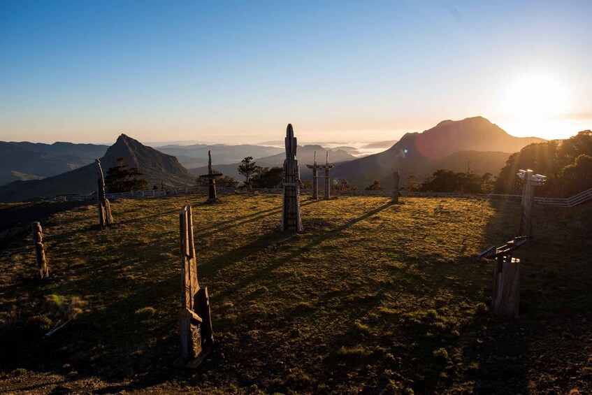 A landscape with a clear sky, a mountain range in the distance, and a fence with wooden posts. 3