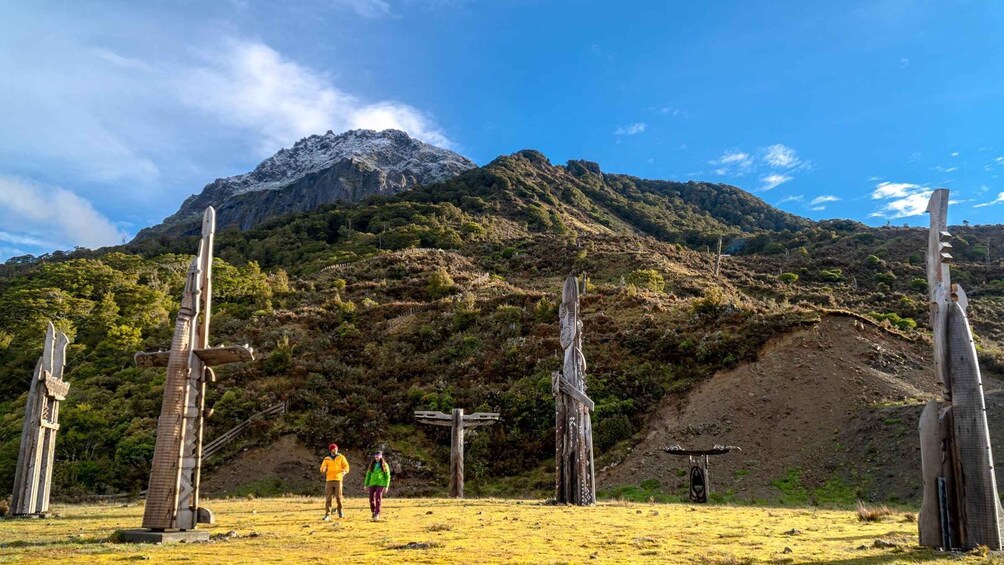 A mountainous landscape with wooden structures and two people walking. 5