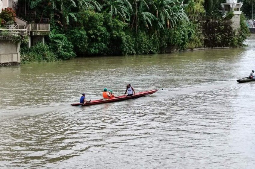 A river with two boats, one red and one black, with people in them. 4