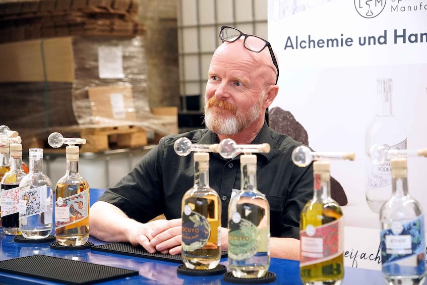 A man sitting at a table with various bottles of alcohol. 3