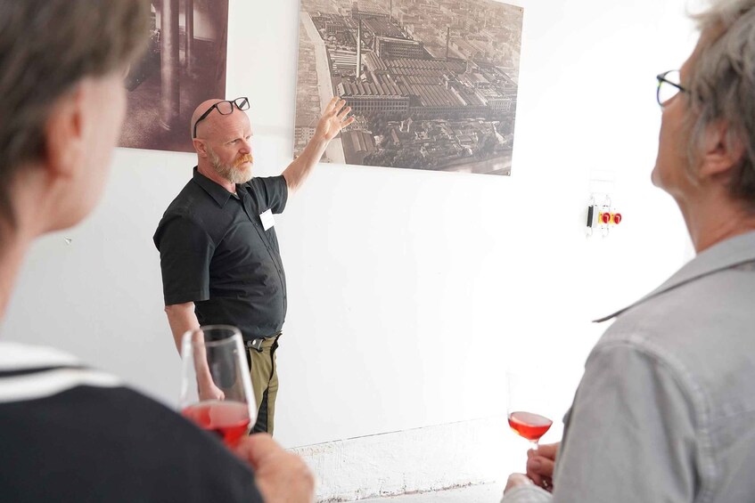 A man presenting to a group, with a cityscape poster on the wall behind him. 2