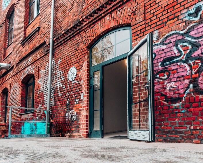 A red brick building with graffiti on the wall and a door. 5