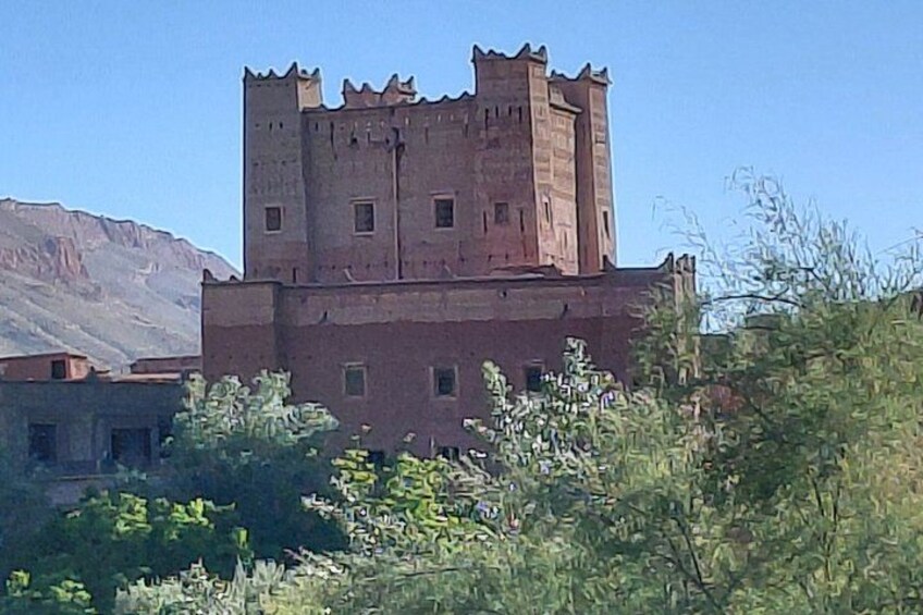 A castle with a tower, surrounded by greenery and mountains in the background. 4