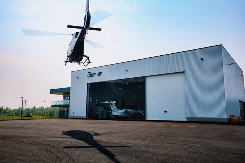 A helicopter hovering above a hangar with a shadow on the ground. 2