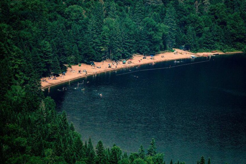 A beach with people and boats, surrounded by dense forest. 5