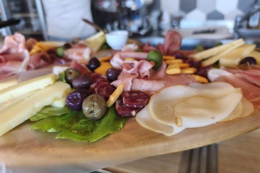 A charcuterie board with various meats, cheeses, olives, and nuts. 5