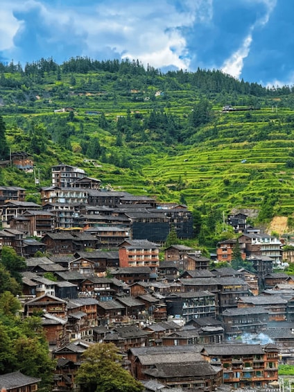 A village with traditional wooden houses nestled in terraced fields on a hillside. 3