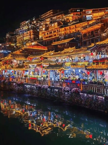 A night view of a traditional Chinese town with illuminated buildings and a river reflecting the lights. 4