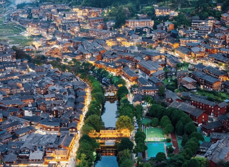 A densely packed town with traditional architecture, a river running through the center, and a bridge connecting two sides. 1