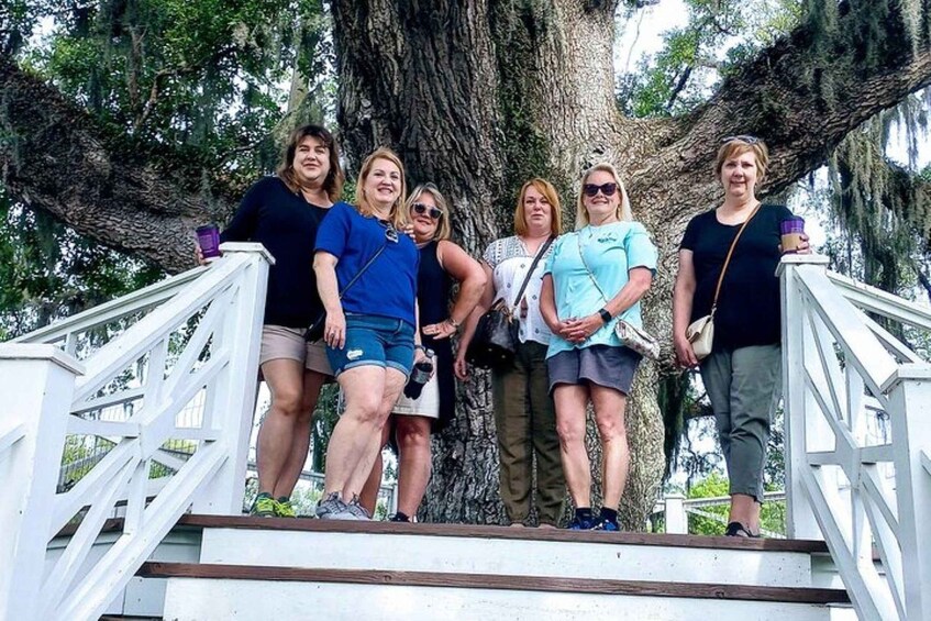 A group of people standing on a staircase with a large tree in the background. 2