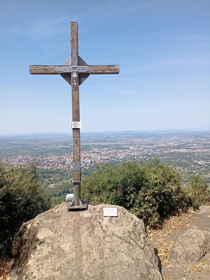 A wooden cross on a rock with a cityscape in the background. 2