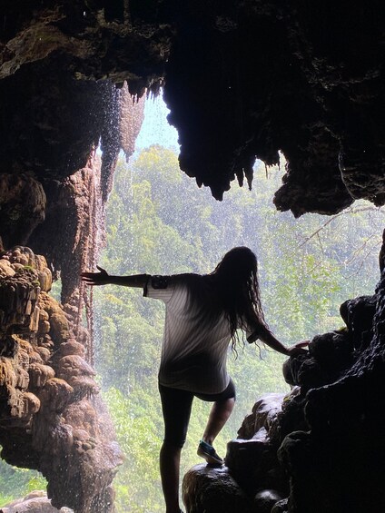 A person standing on rocks inside a cave with water dripping from the ceiling. 1