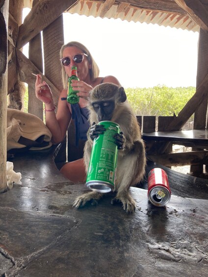 A monkey holding a can, a woman with a bottle, and a can on the ground. 5